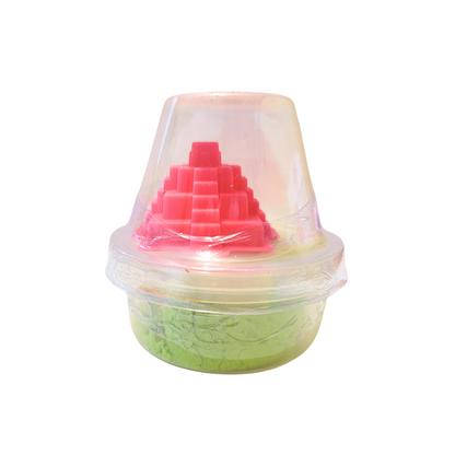 A container of green sensory sand with a pink Chichen Itza inspired castle mold.
