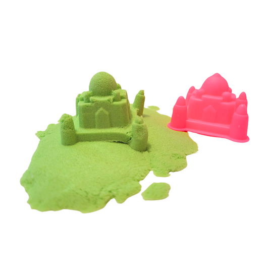Green sensory sand is spread out, with a mini Taj Mahal inspired castle made out of some of the sensory sand. To the right of the castle is the pink Taj Mahal inspired castle mold.