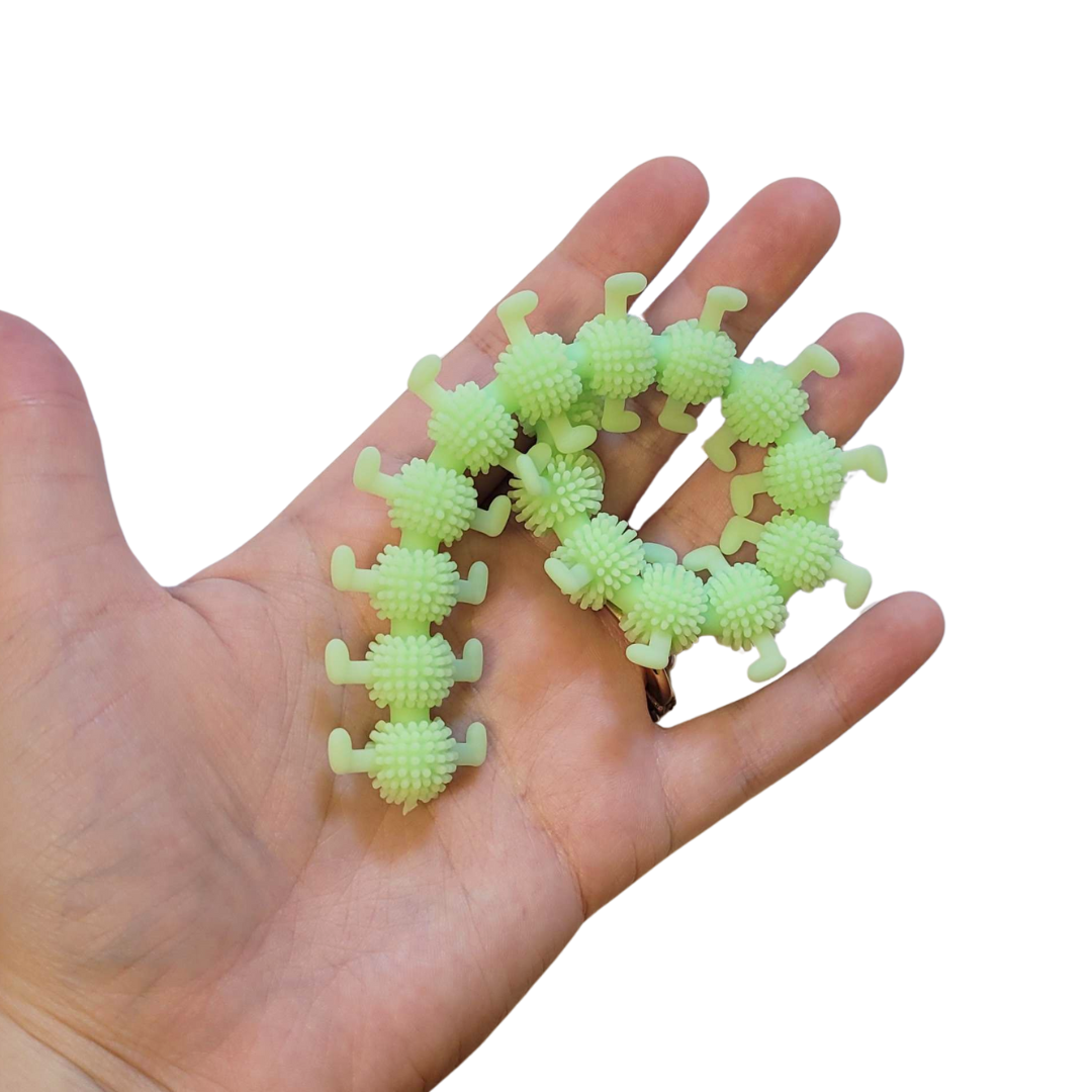A person's hand holds out a lime green stretchy caterpillar.