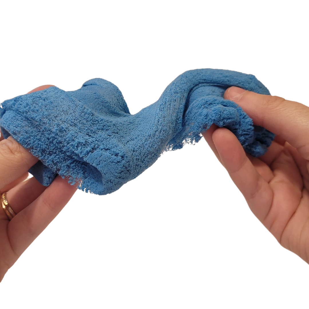 A person's hands stretch and twist blue Sticky Sand.