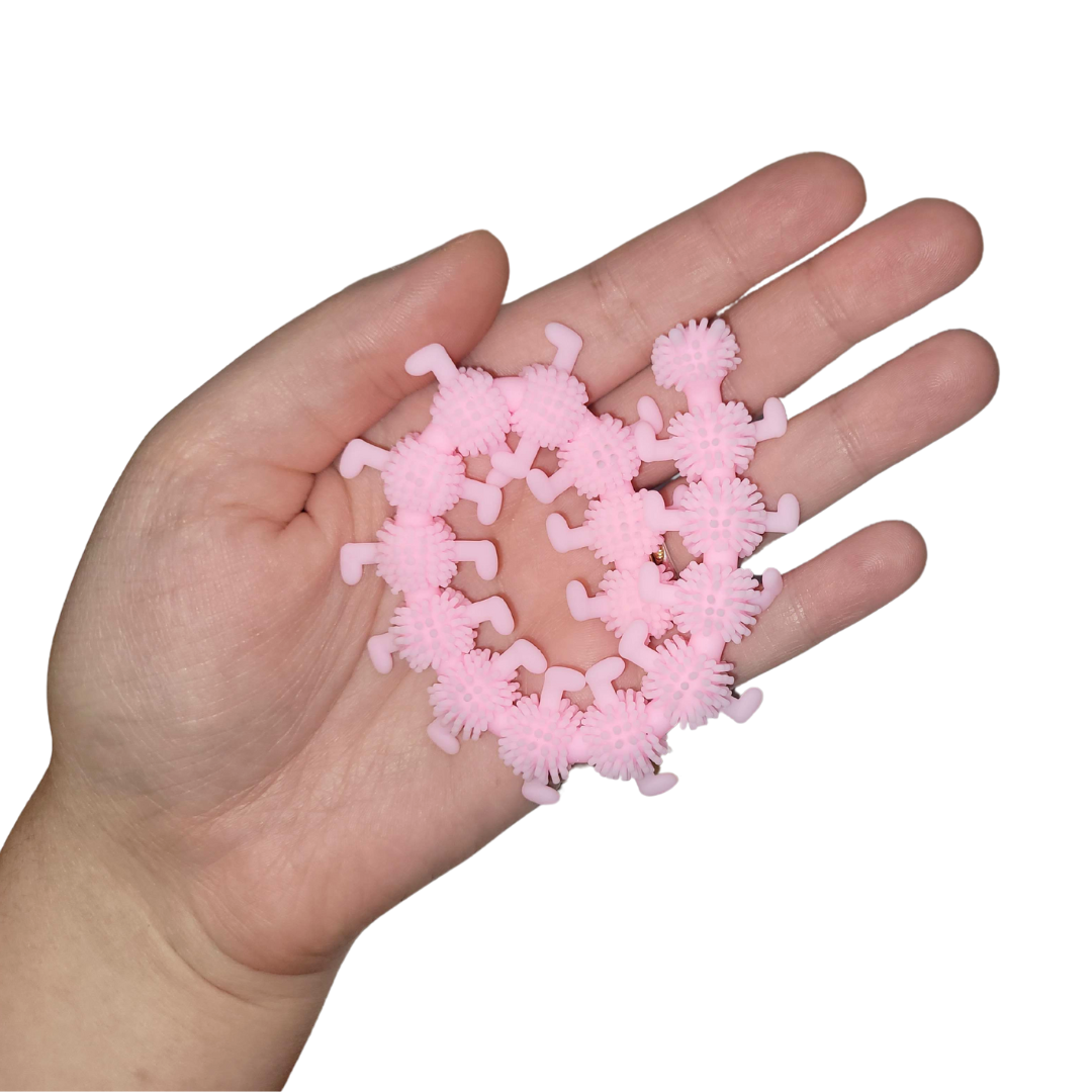 A person's hand holds out a light pink stretchy caterpillar.