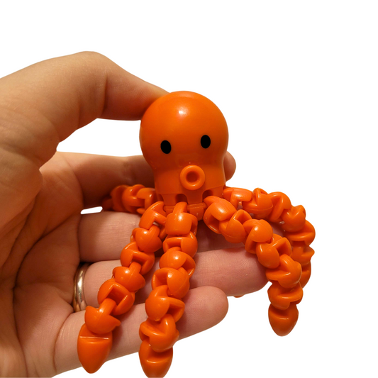 A person's hand holds an orange fidget octopus.