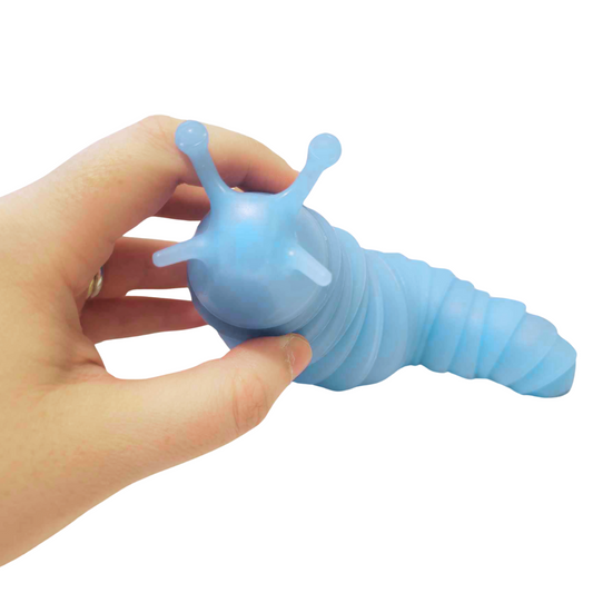 A person's hand holds a light blue Super Sensory Glow-in-the-Dark Fidget Slug.