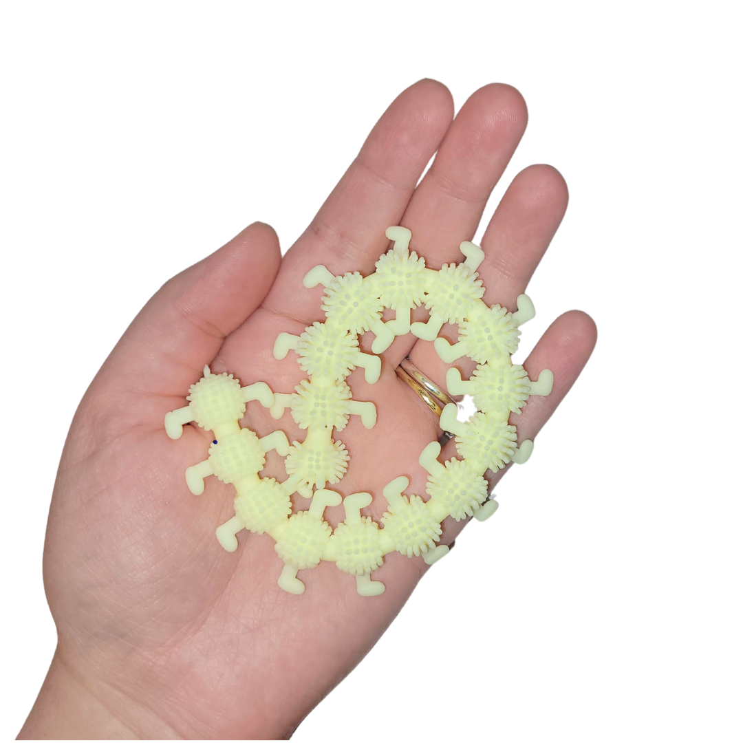 A person's hand holds out a pastel yellow stretchy caterpillar.