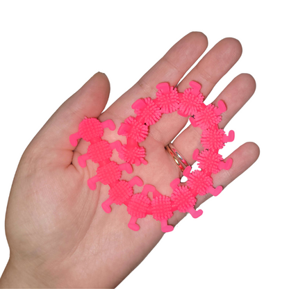 A person's hand holds out a hot pink stretchy caterpillar.