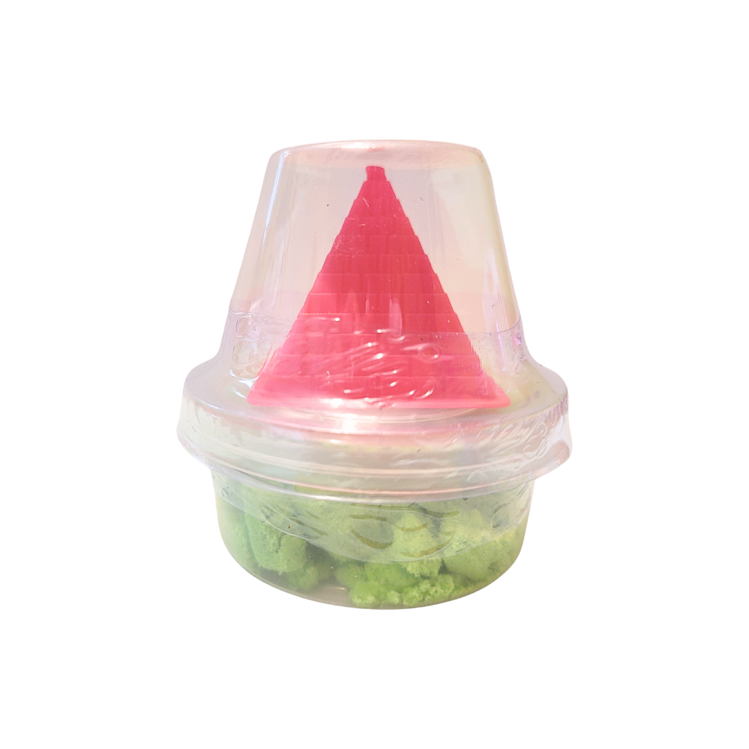 A container of green sensory sand with a pink pyramid castle mold.