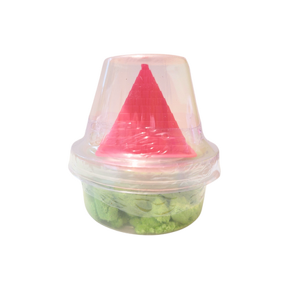 A container of green sensory sand with a pink pyramid castle mold.