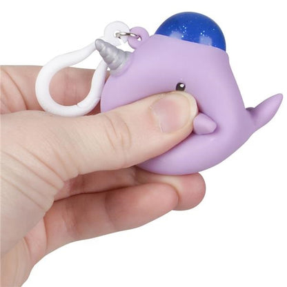 A person's hand squeezes a purple squishy narwhal keychain.