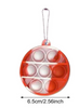 A circular shaped red and white tie dye bubble pop fidget keychain. Below it is an arrow with measurements below it. Measurements reads: "6.5cm slash 2.56 inches wide."