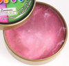 A close up of an open container of pink iridescent, sparkly putty.